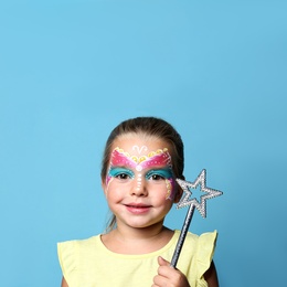 Cute little girl with face painting on blue background