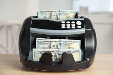 Modern electronic bill counter with money on table indoors