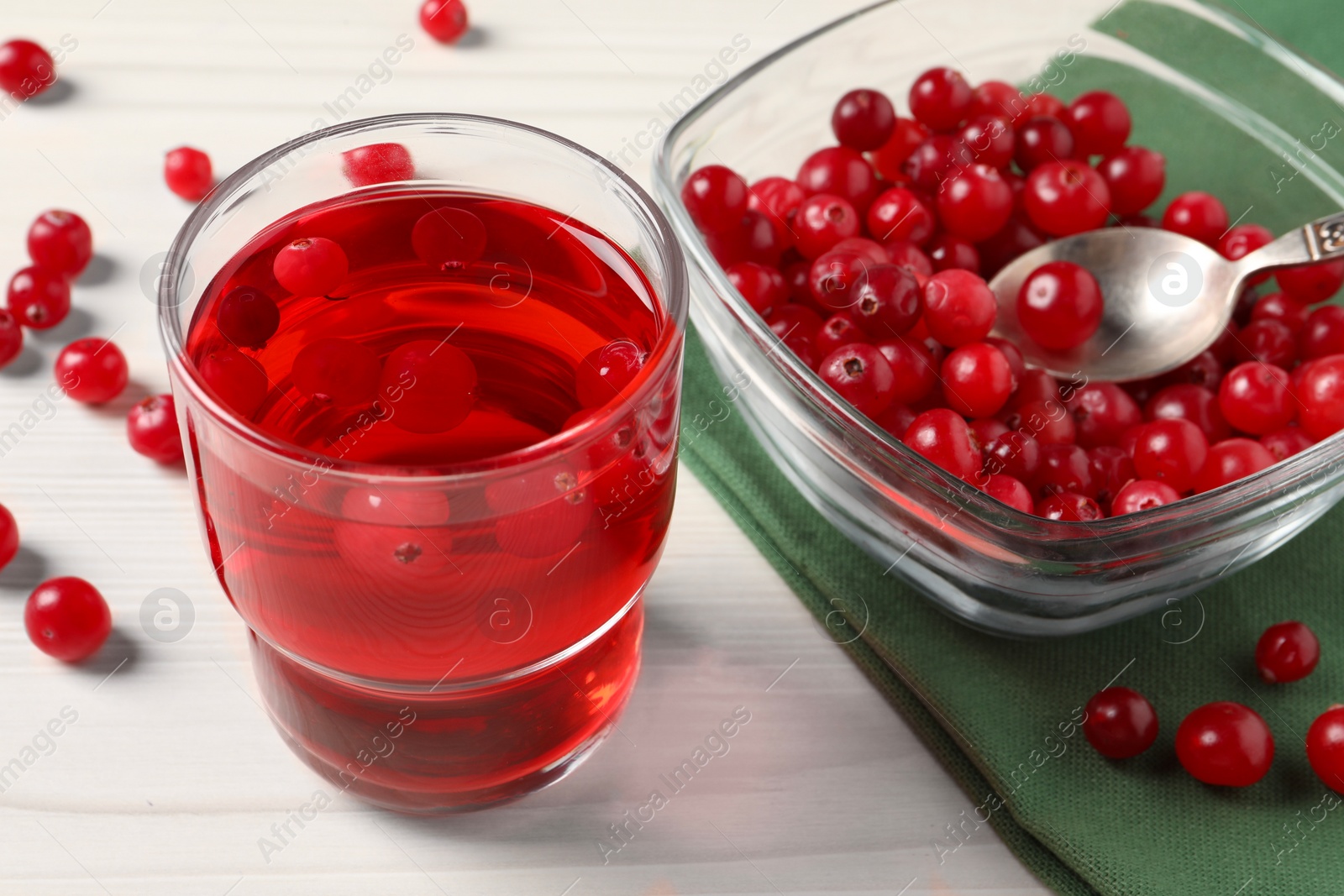 Photo of Tasty cranberry juice in glass and fresh berries on white wooden table, closeup