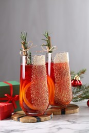 Photo of Christmas Sangria cocktail in glasses and festive decor on white marble table