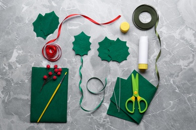 Photo of Set of instruments and materials for making mistletoe branch on grey table, flat lay
