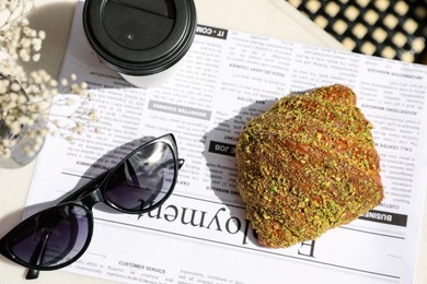 Delicious croissant, paper cup and sunglasses on table, flat lay