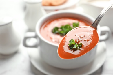 Photo of Spoon with fresh homemade tomato soup on blurred background, closeup. Space for text