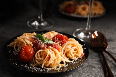 Photo of Tasty pasta with basil, tomatoes and cheese on grey table