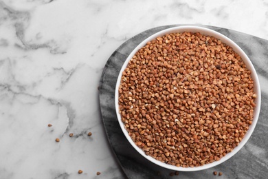 Buckwheat grains on white marble table, top view. Space for text