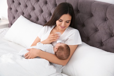 Woman feeding her baby from bottle on bed