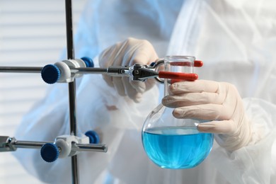 Scientist working with flask of light blue liquid in laboratory, closeup