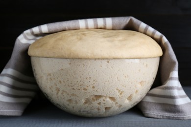Photo of Bowl of fresh yeast dough on grey wooden table, closeup