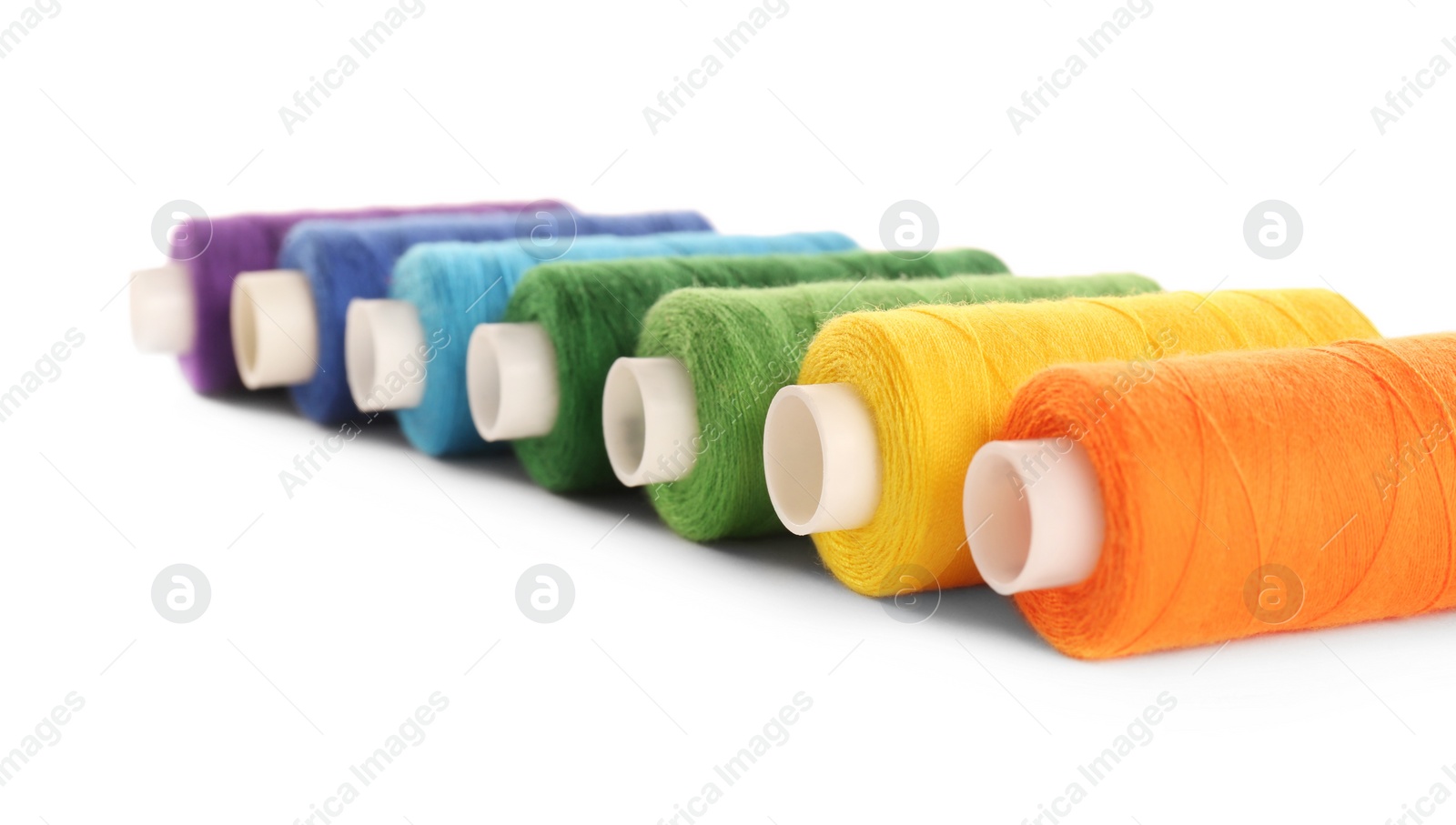 Photo of Set of colorful sewing threads on white background