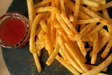 Photo of Above view of delicious hot french fries with red sauce served on table, closeup