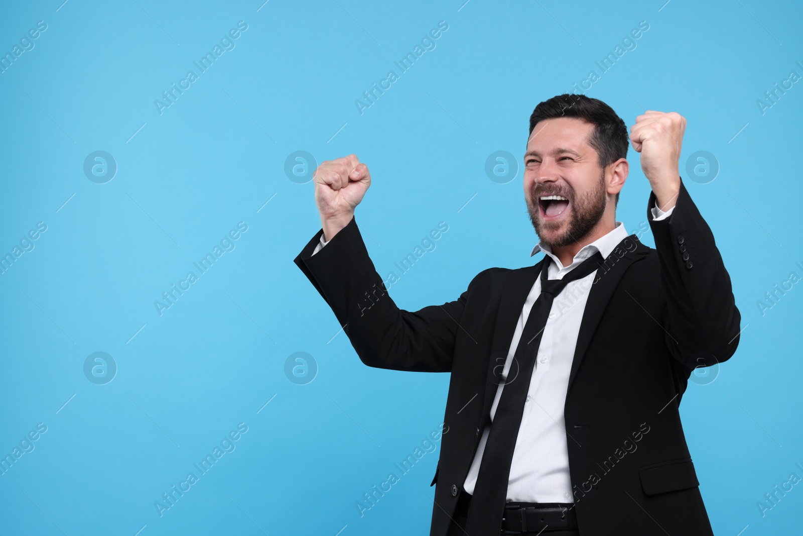 Photo of Emotional sports fan celebrating on light blue background. Space for text