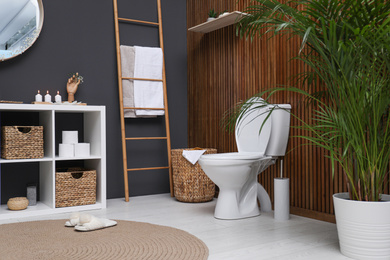 Photo of Elegant modern bathroom with toilet bowl near wooden wall