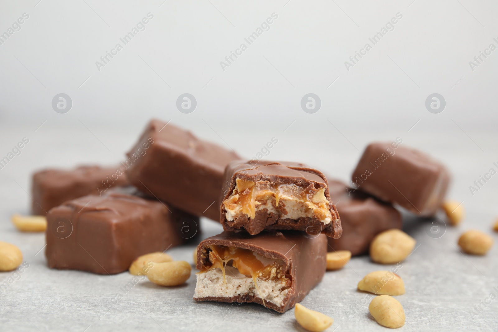 Photo of Chocolate bars with caramel, nuts and nougat on light grey table, closeup