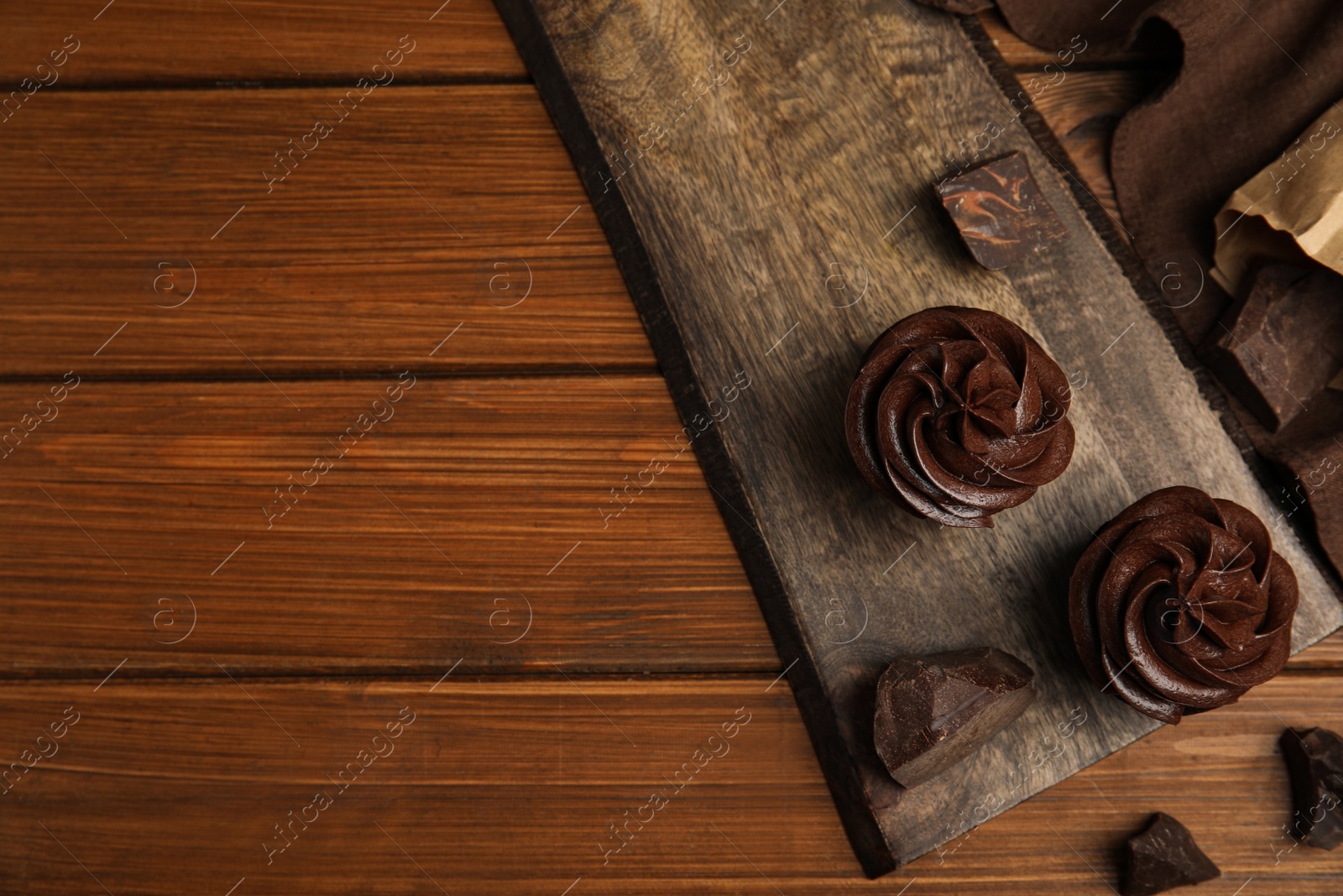Photo of Flat lay composition with delicious chocolate cupcakes on wooden table. Space for text