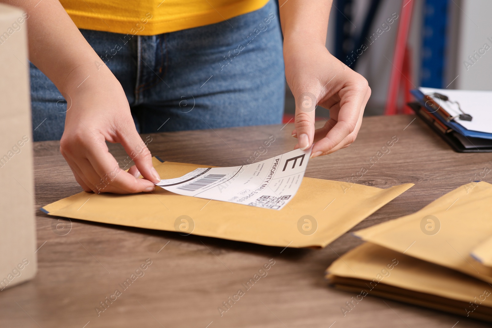 Photo of Post office worker sticking barcode on parcel at counter indoors, closeup