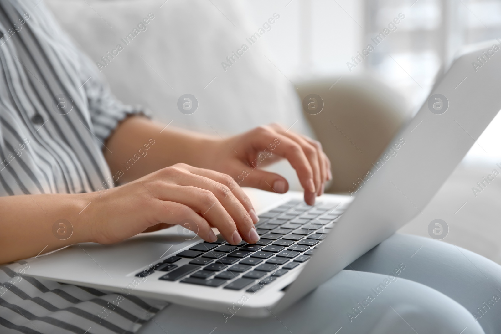 Photo of Young woman using laptop indoors, closeup