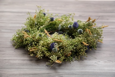 Photo of Beautiful wreath made of wildflowers on wooden background
