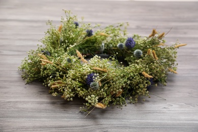 Beautiful wreath made of wildflowers on wooden background