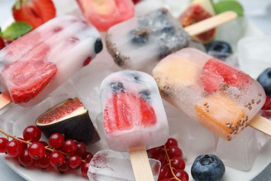 Photo of Tasty refreshing fruit and berry ice pops on table, closeup