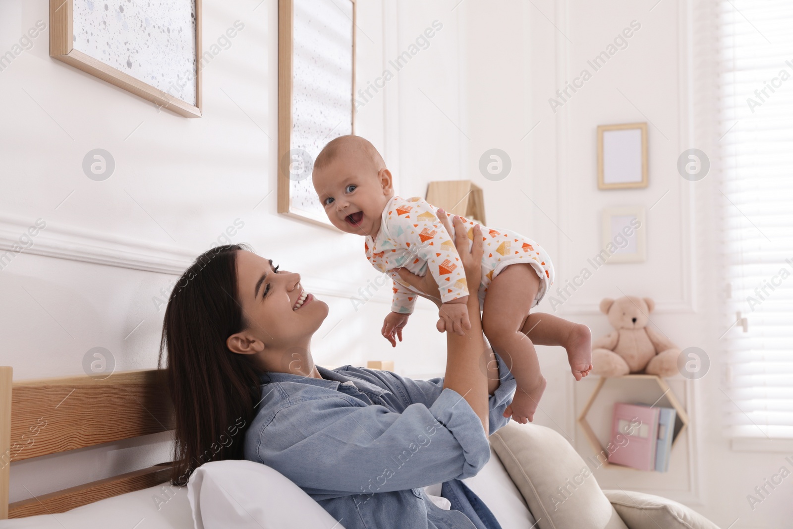 Photo of Mother with her cute baby on bed at home