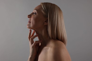 Photo of Beautiful woman touching her neck on grey background