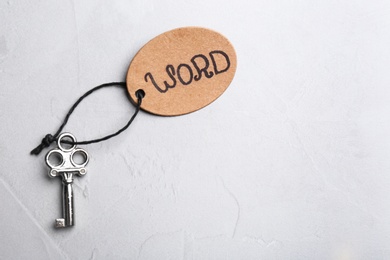 Photo of Key and tag WORD on grey table, top view. Keyword concept