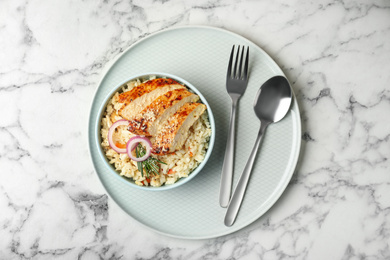 Photo of Delicious chicken risotto served on white marble table, top view