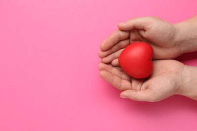 Photo of Man holding red decorative heart on pink background, top view and space for text. Cardiology concept