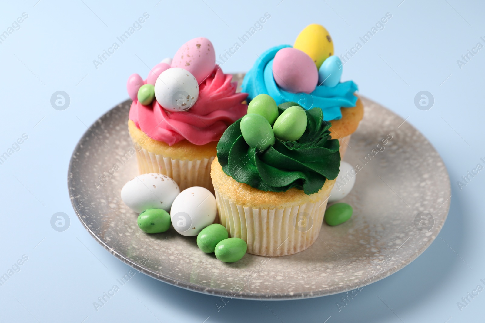 Photo of Tasty cupcakes with Easter decor on light blue background