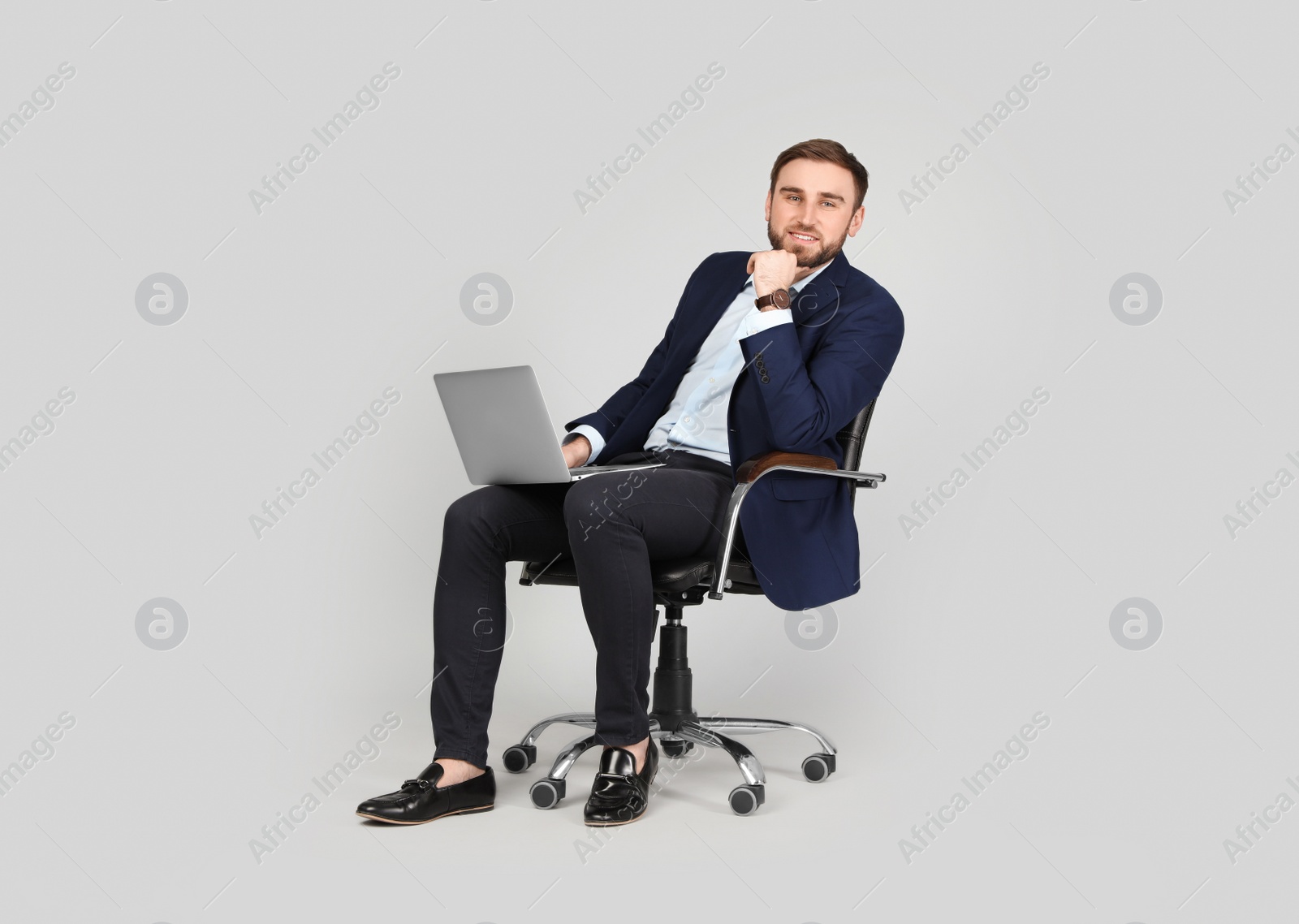 Photo of Young businessman with laptop sitting in comfortable office chair on grey background