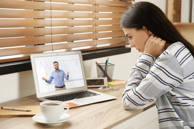 Image of Young woman watching video at desk indoors. Online learning