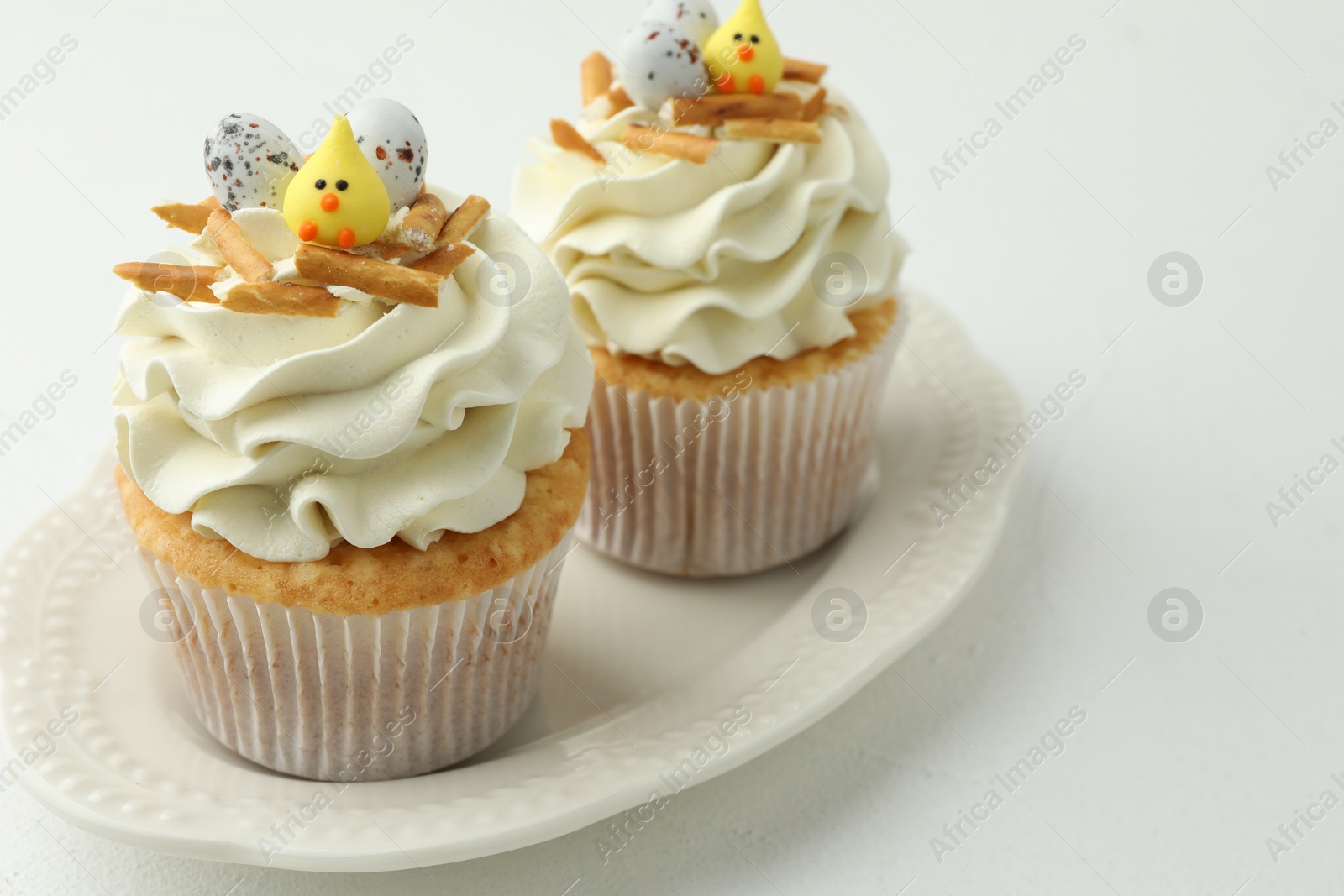 Photo of Tasty Easter cupcakes with vanilla cream on white table, closeup. Space for text