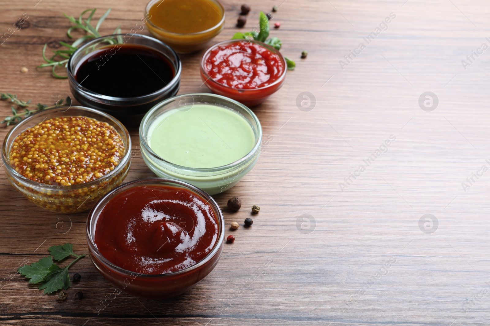 Photo of Many different sauces on wooden table, space for text