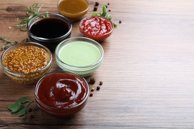 Many different sauces on wooden table, space for text