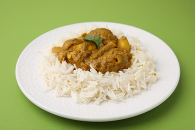 Photo of Delicious chicken curry with rice on green background, closeup