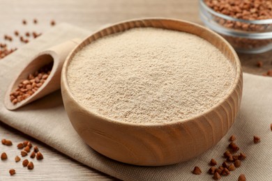 Photo of Bowl with buckwheat flour and seeds on wooden table, closeup