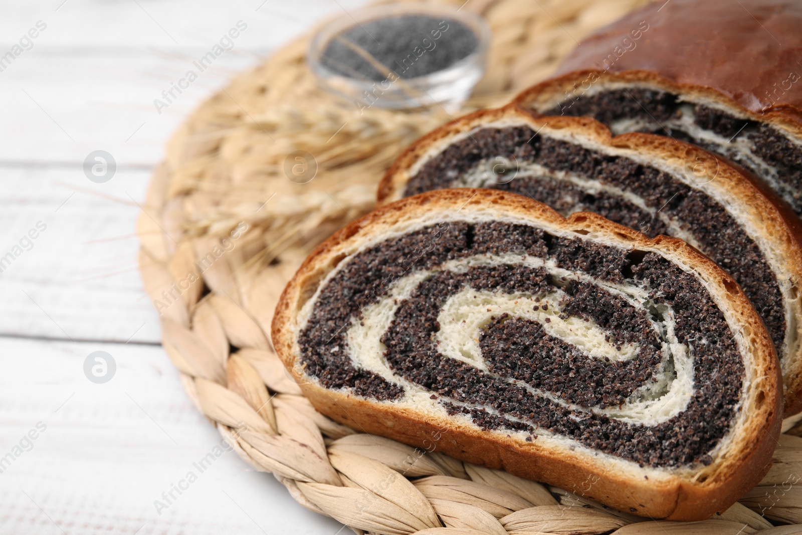 Photo of Cut poppy seed roll on white wooden table, closeup with space for text. Tasty cake