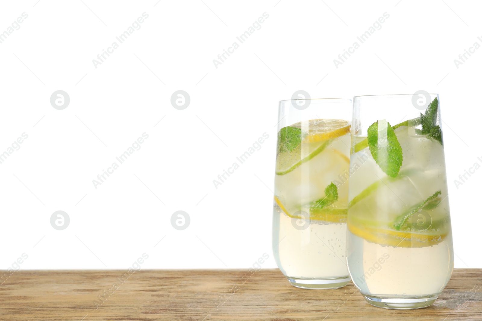 Photo of Glasses of refreshing lemonade on wooden table against white background, space for text. Summer drink
