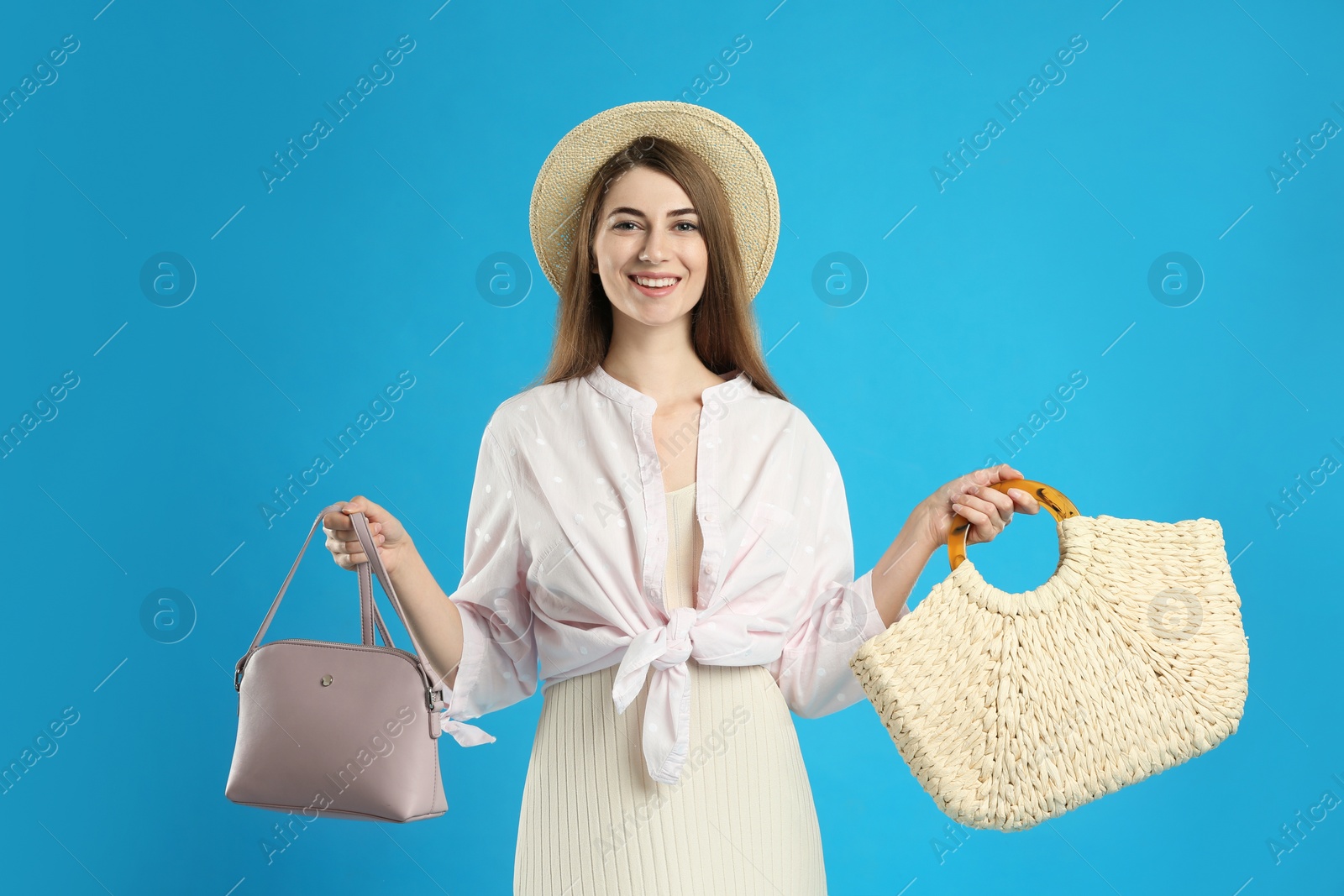 Photo of Beautiful young woman with stylish bags on light blue background