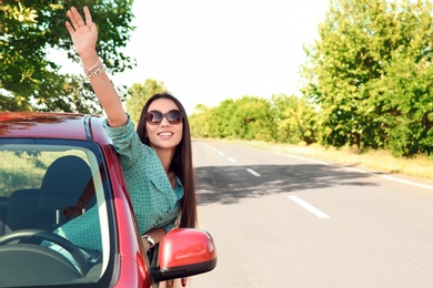 Young woman leaning out of car window