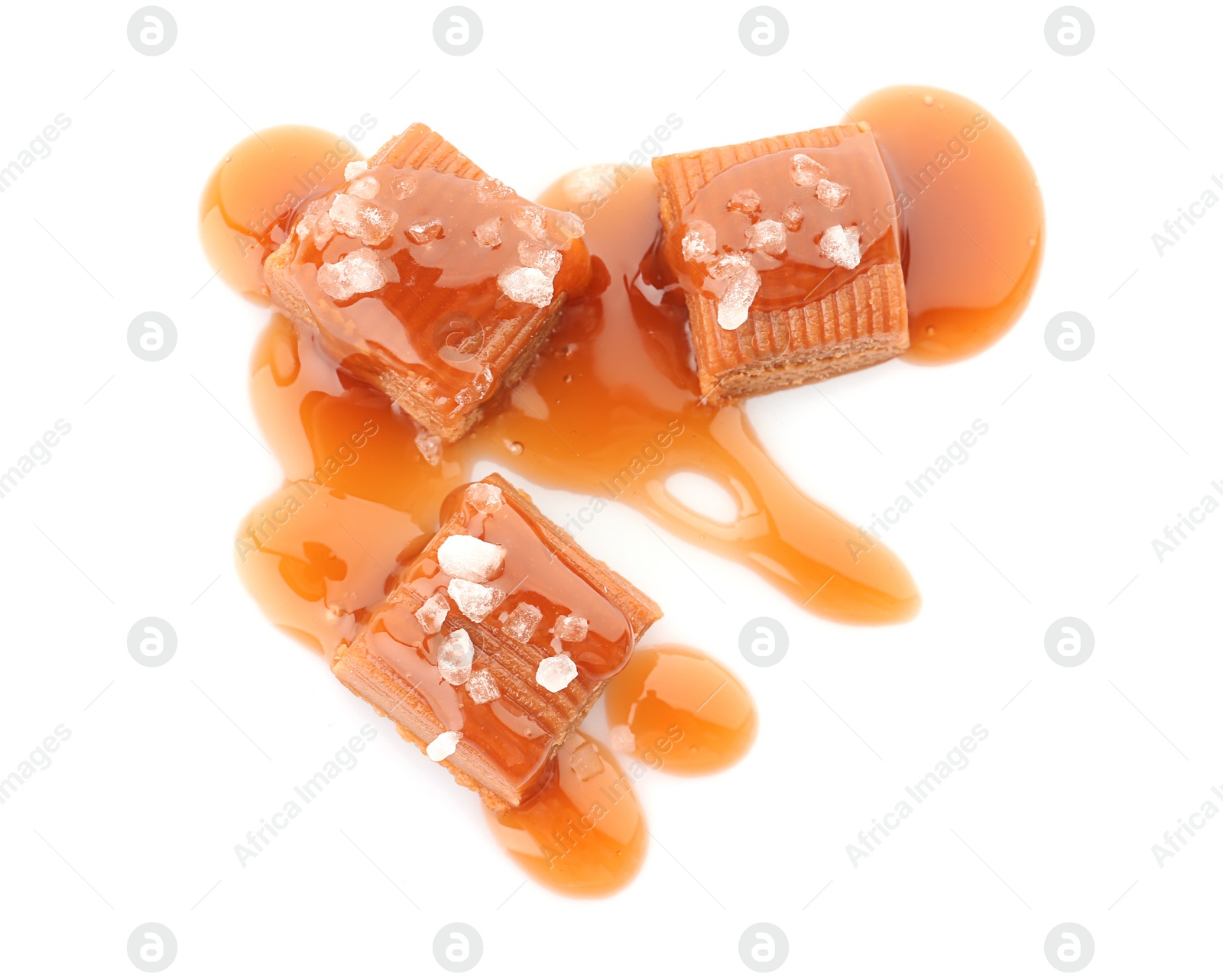 Photo of Delicious candies with caramel sauce and salt on white background