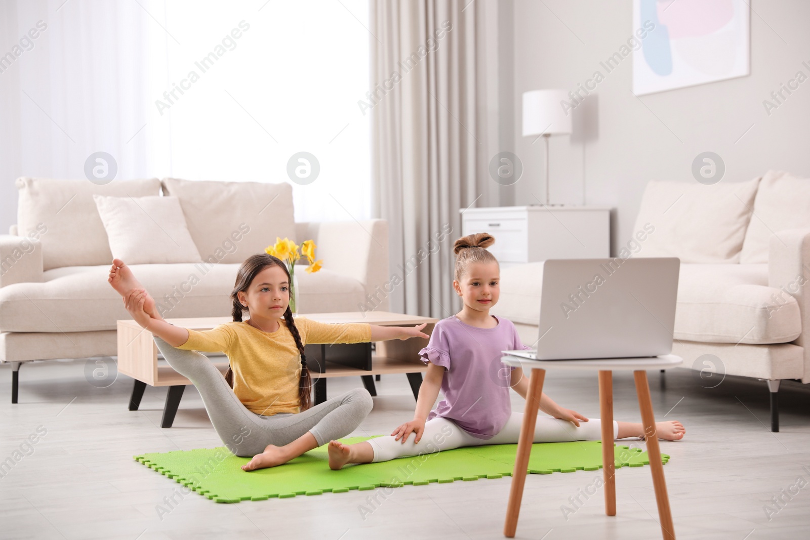 Photo of Cute little girls warming up before online dance class at home