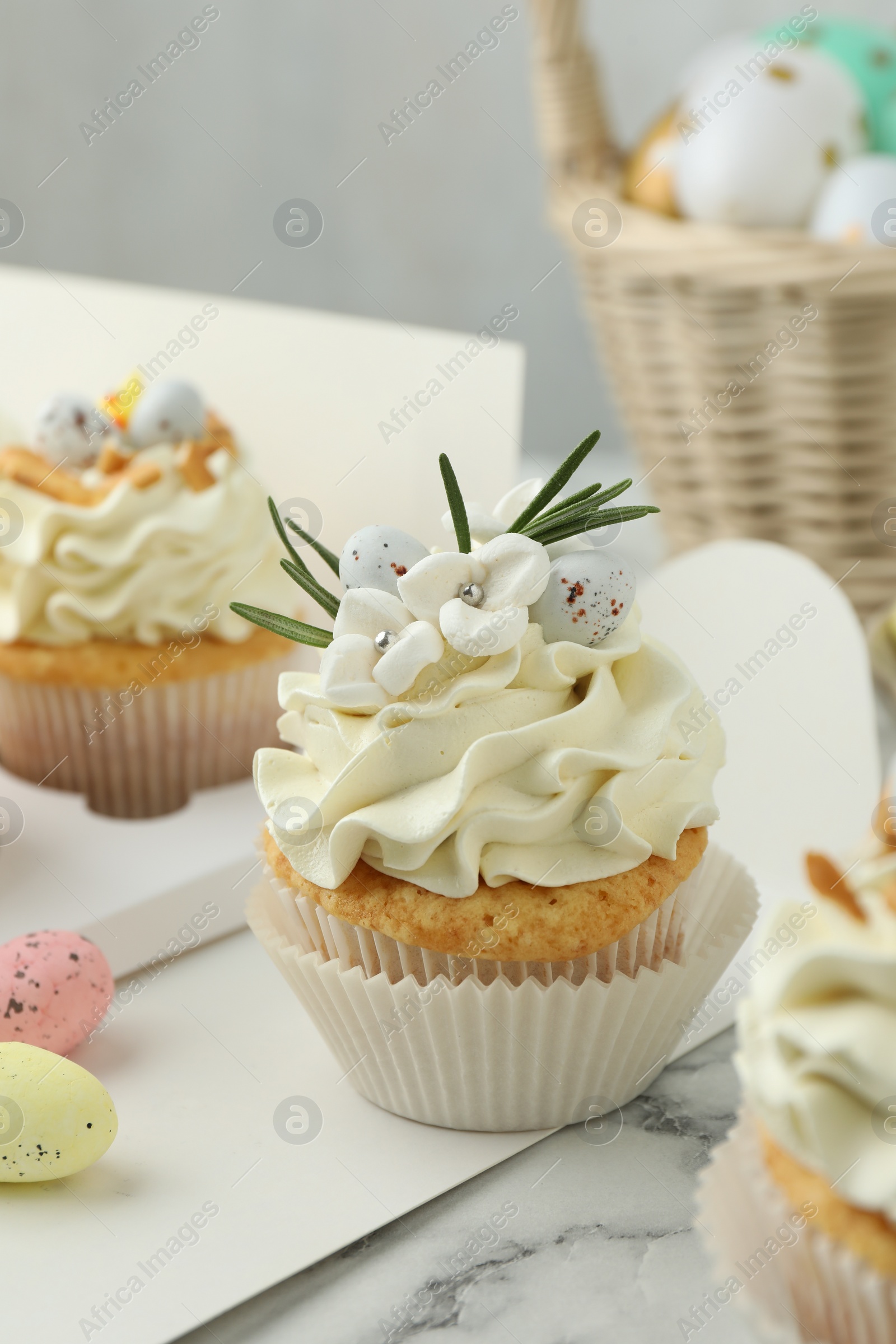 Photo of Tasty Easter cupcakes with vanilla cream on white marble table