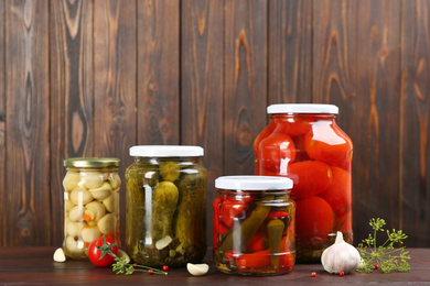 Photo of Jars of pickled vegetables on wooden table