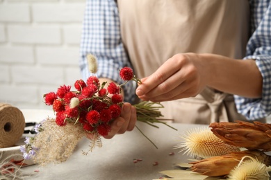 Photo of Florist making bouquet of dried flowers at light grey table, closeup
