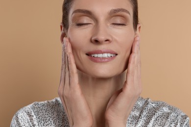 Woman massaging her face on beige background
