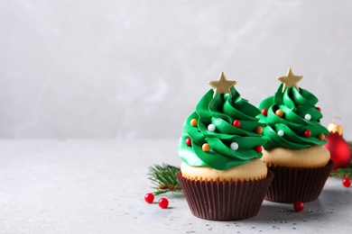 Photo of Christmas tree shaped cupcakes on light grey table. Space for text