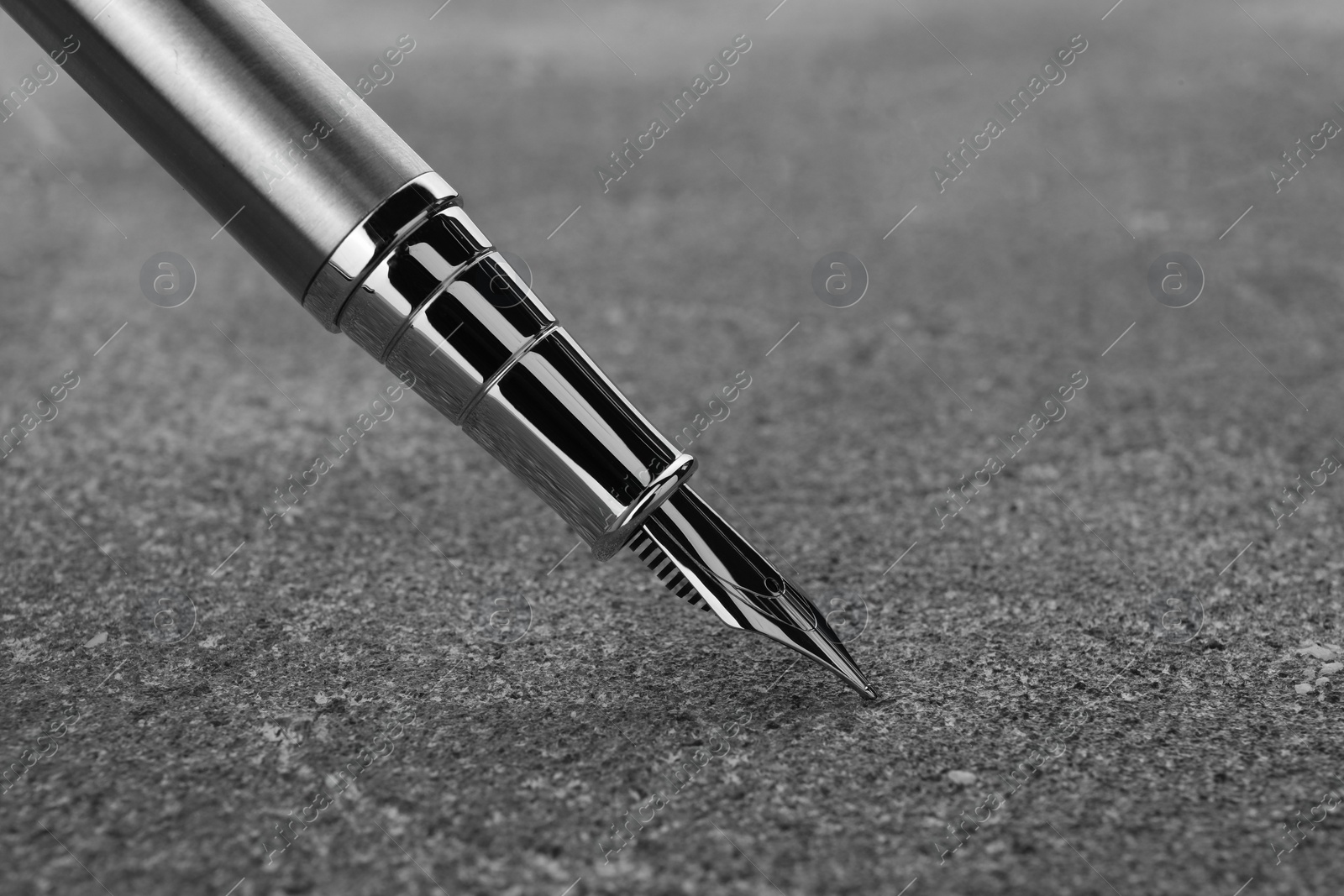 Photo of Stylish silver fountain pen on grey textured table, closeup