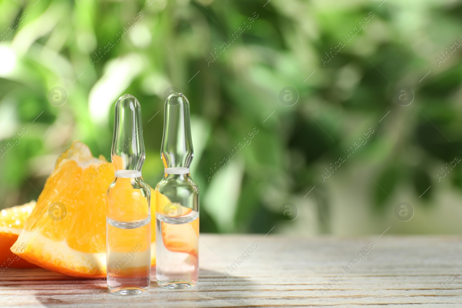 Photo of Pharmaceutical ampoules with medication and orange slices on white wooden table, space for text