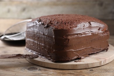 Delicious homemade layer cake with chocolate cream on wooden table, closeup